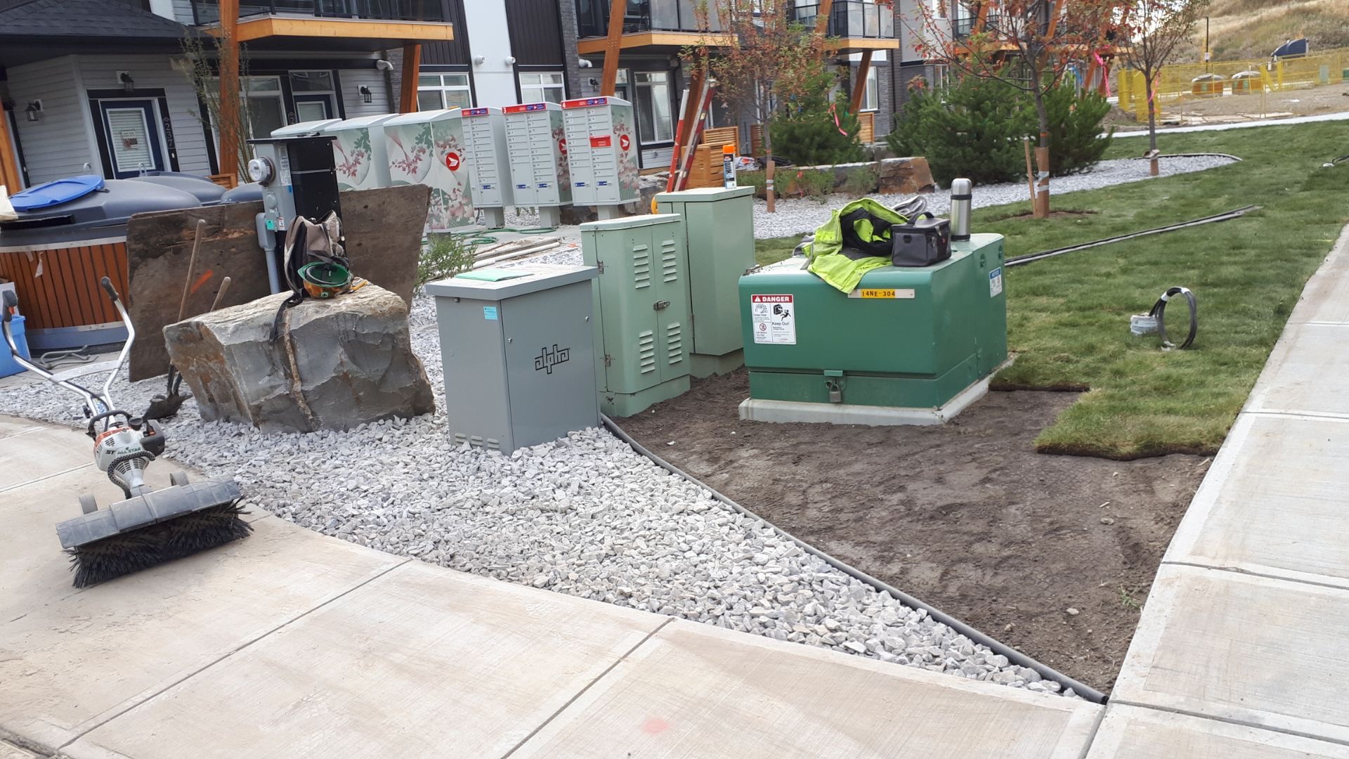 Fresh sod and rock detailing around utility boxes at a new townhome complex