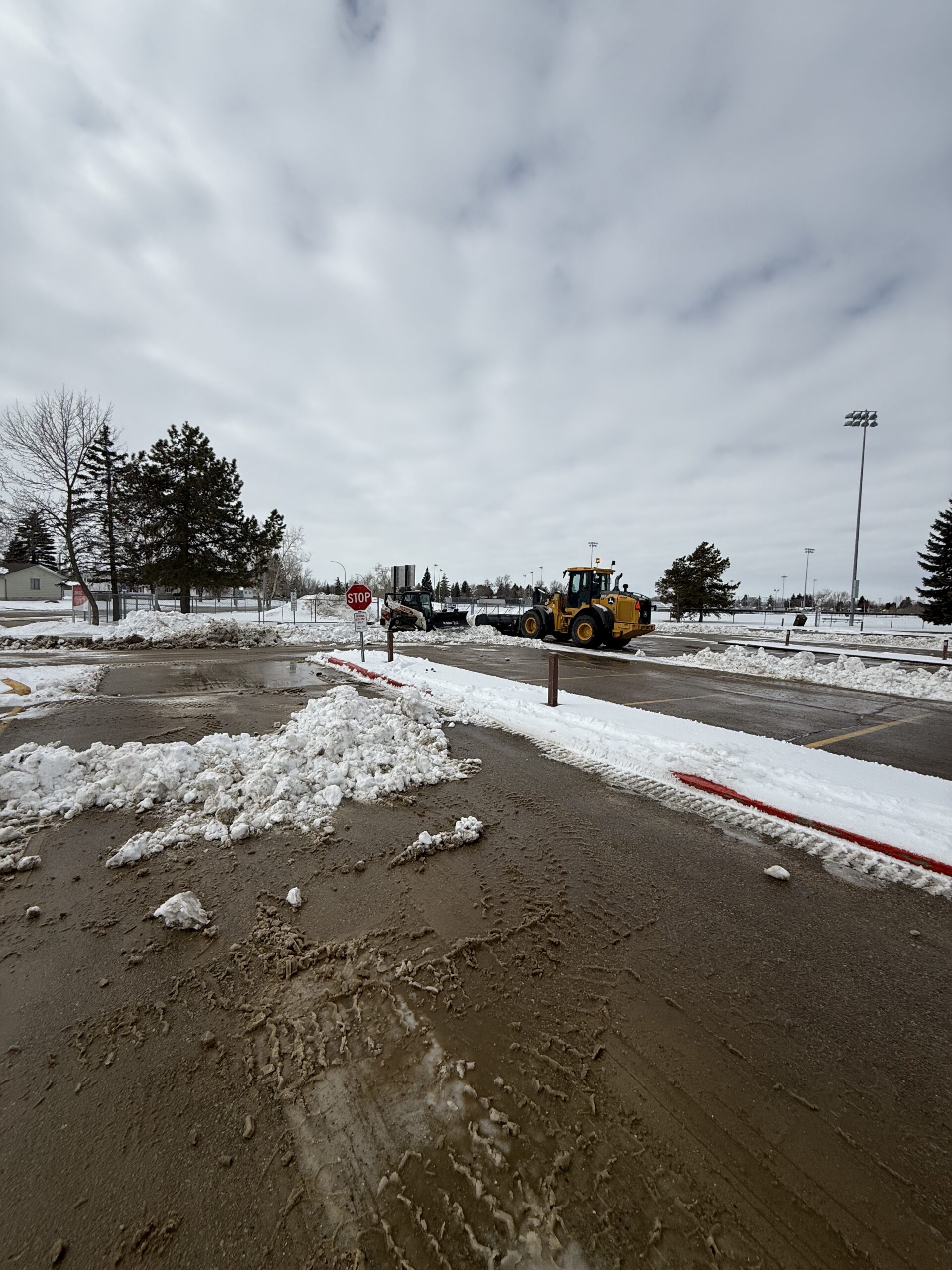 Loader clearing snow across a commercial lot