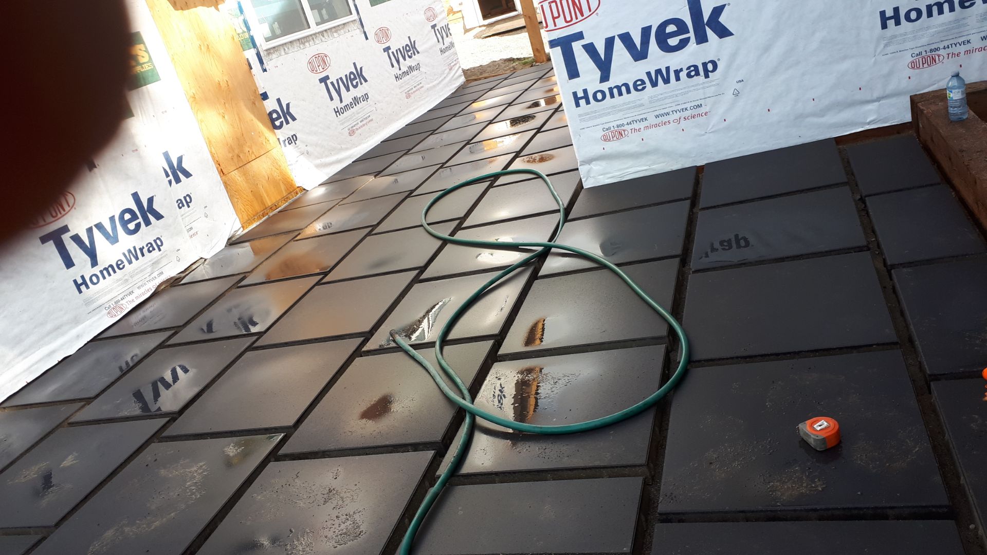 Charcoal paver patio being installed in a new backyard