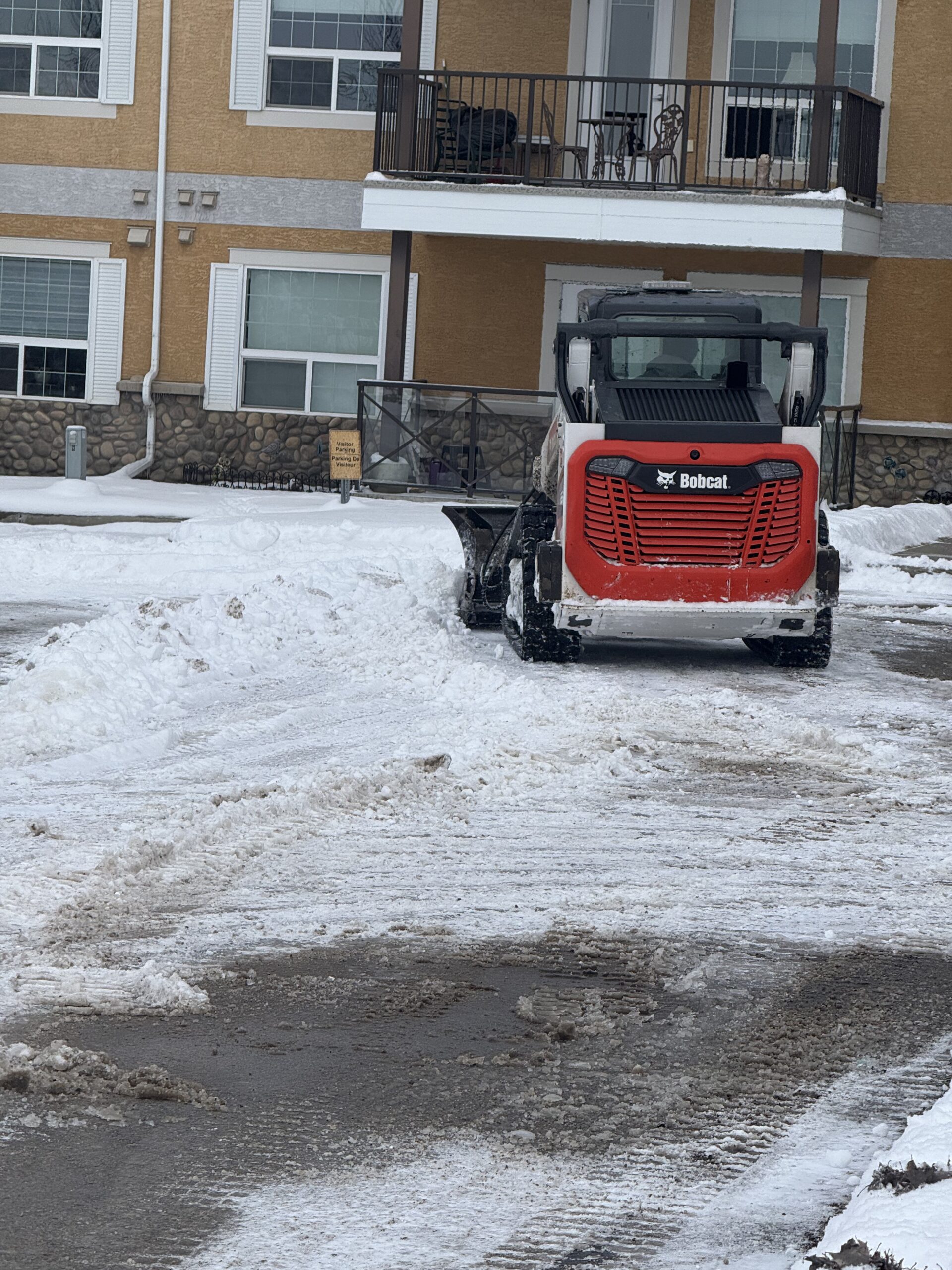 Skid steer clearing snow at a multi-family building entrance