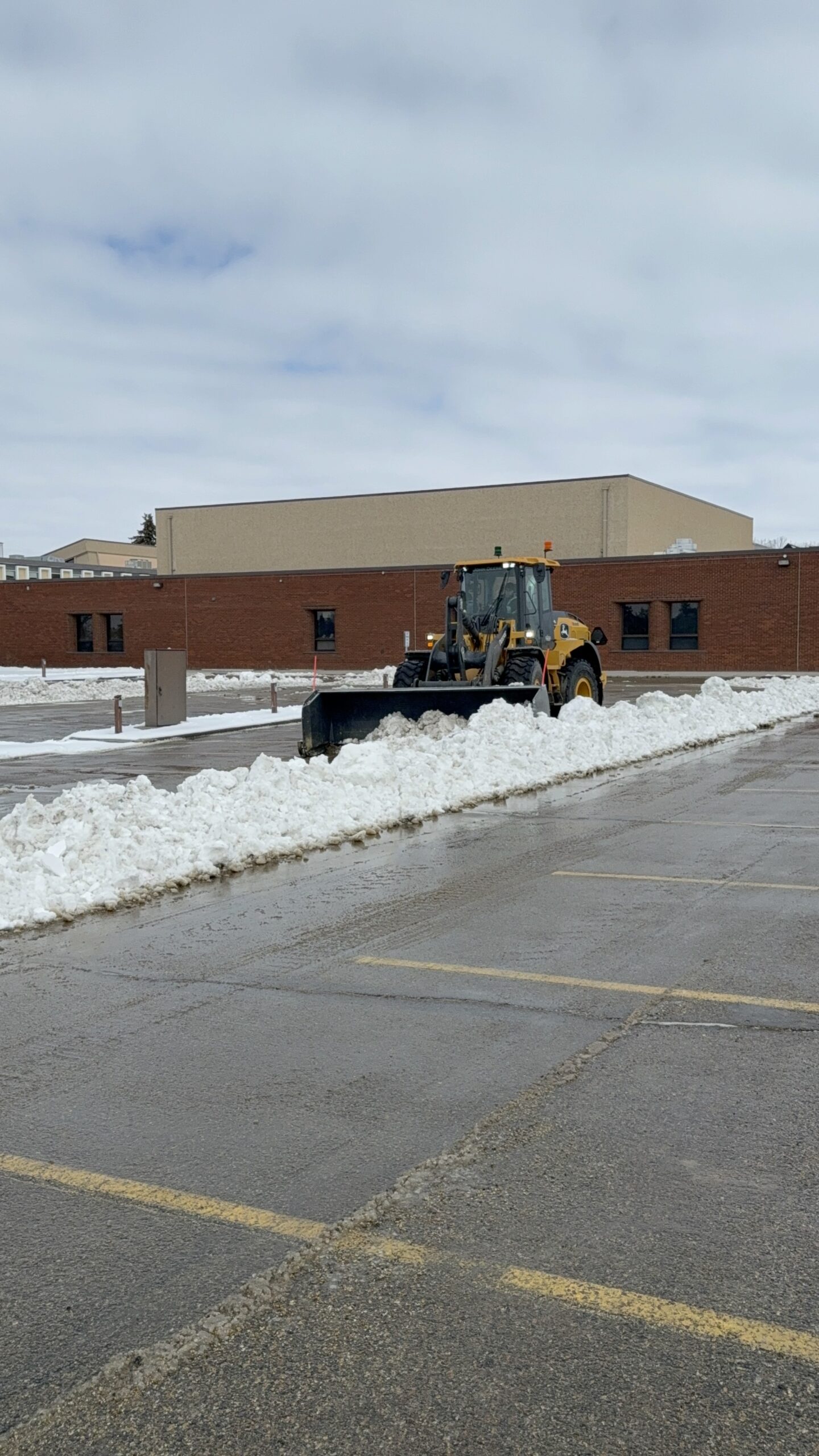 Loader clearing snow across a commercial parking lot