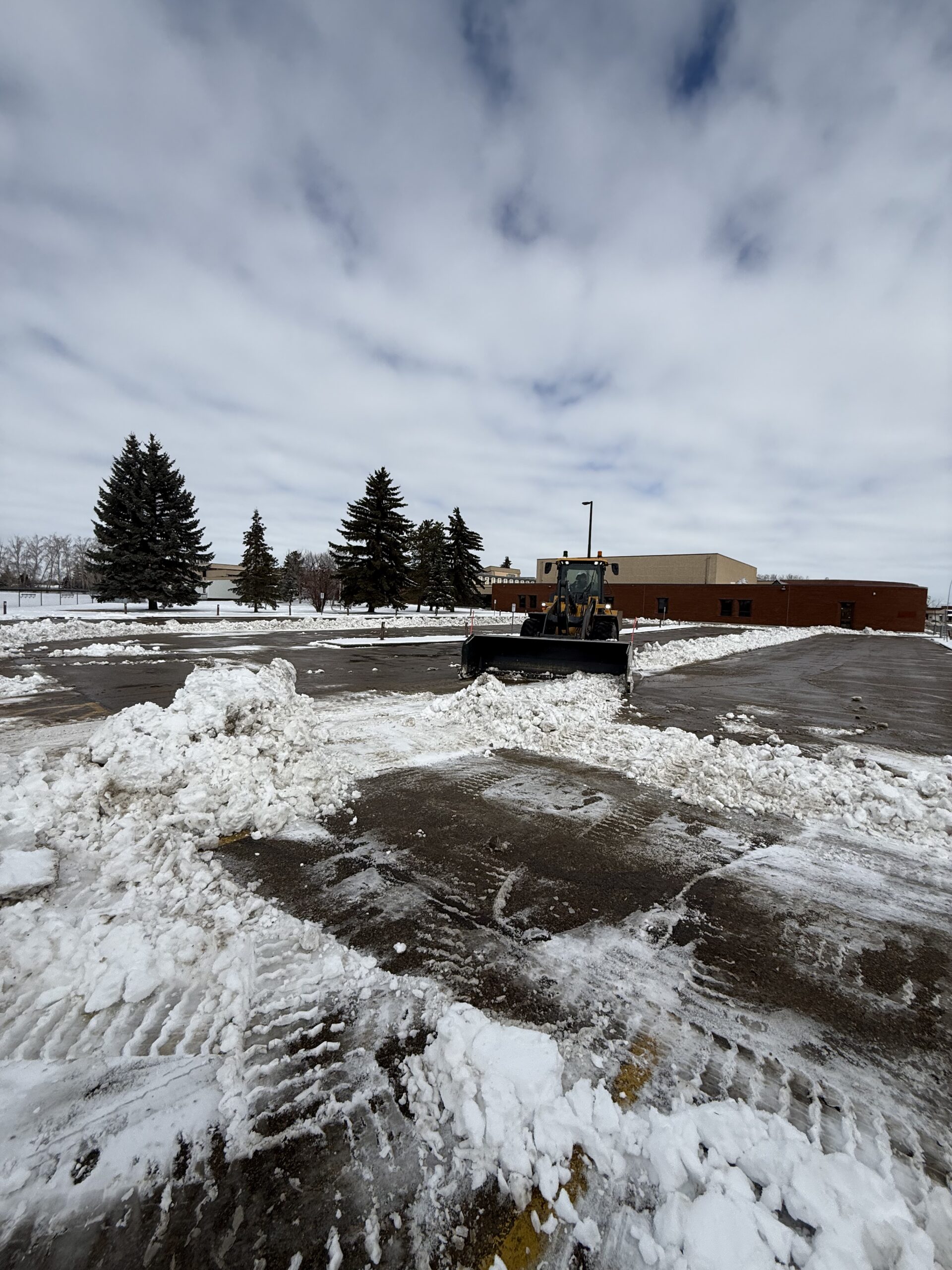 Plow clearing a wide commercial lot after a storm