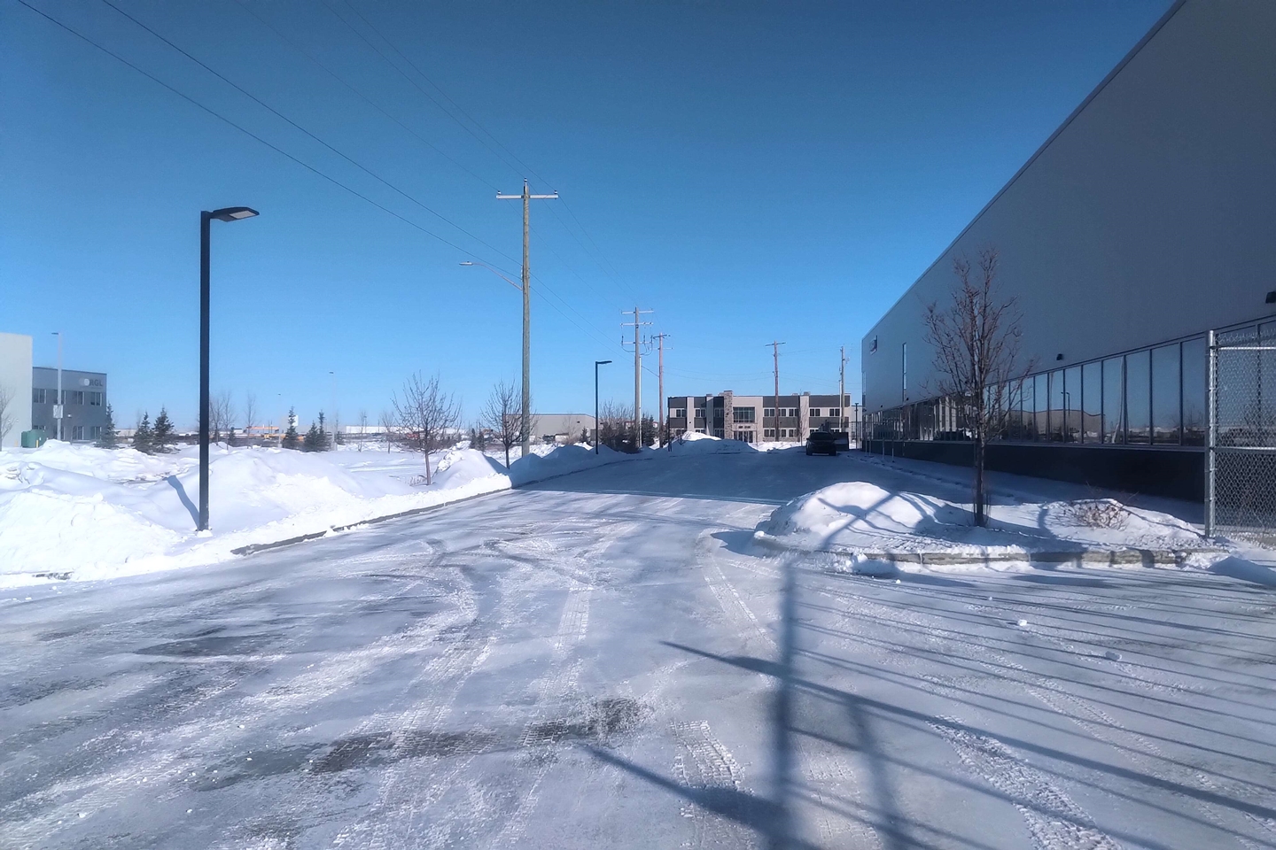 Cleared industrial lot with snow piled along the fence line