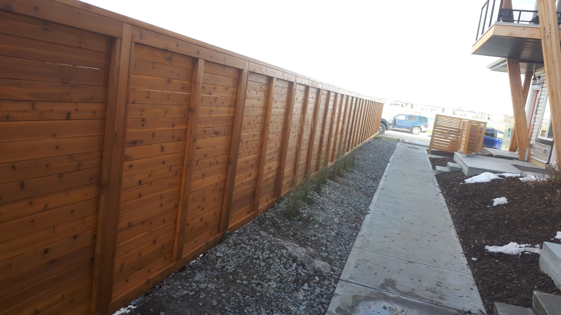 Horizontal cedar privacy fence along a walkway at a multi-family building