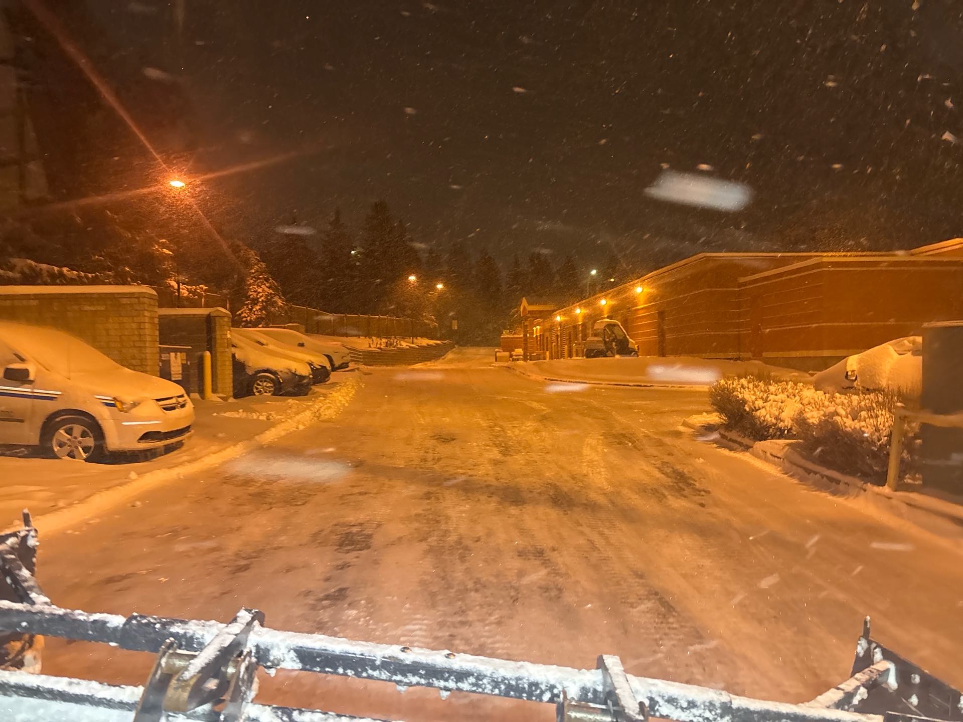 Snow plow clearing a lot during an Alberta snowfall